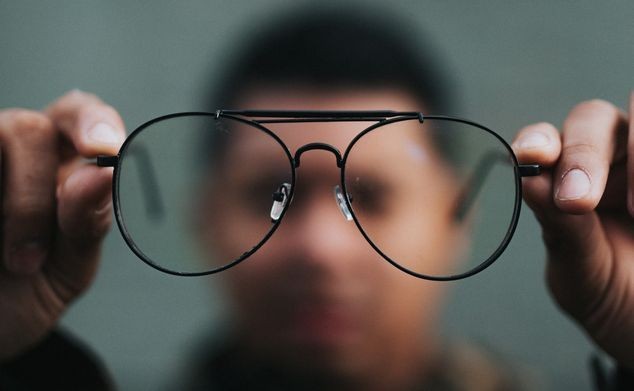 blurry background with a man's face and a pair of glasses in the foreground