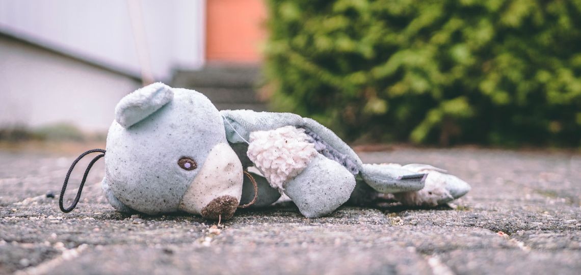 a child's bear left lying on the pavement