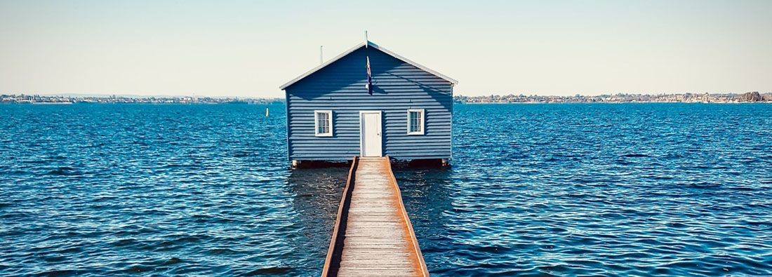 a house in the sea with a wooden pier leading to it