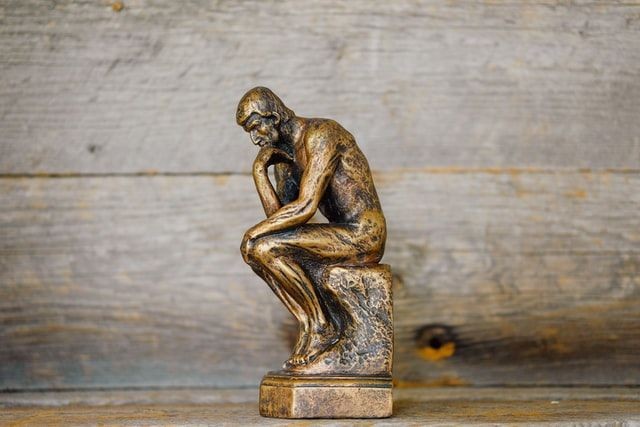 bronze statue of a man sitting and thinking